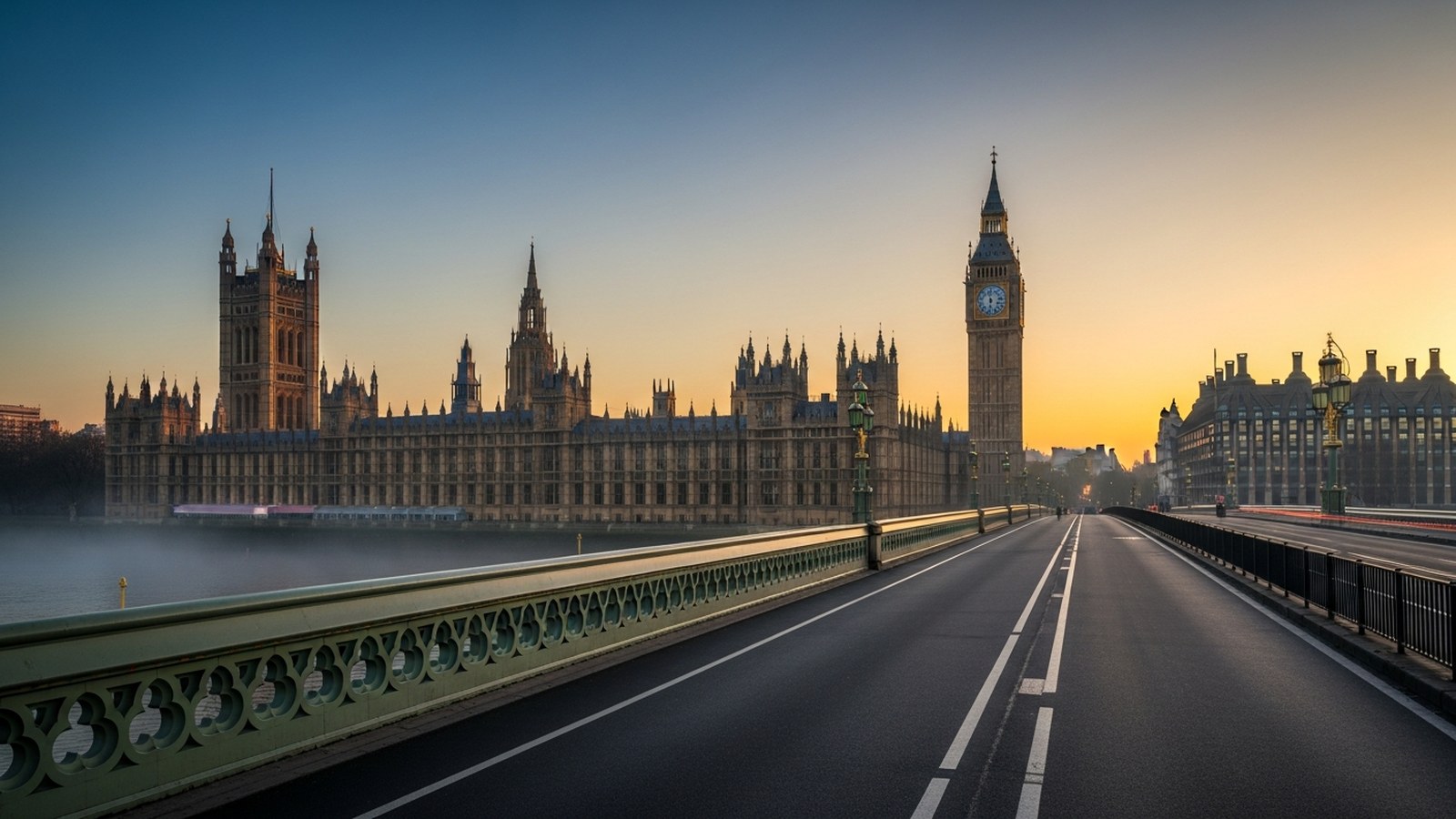 First light over the Palace of Westminster across a misty Thames, the bridge empty